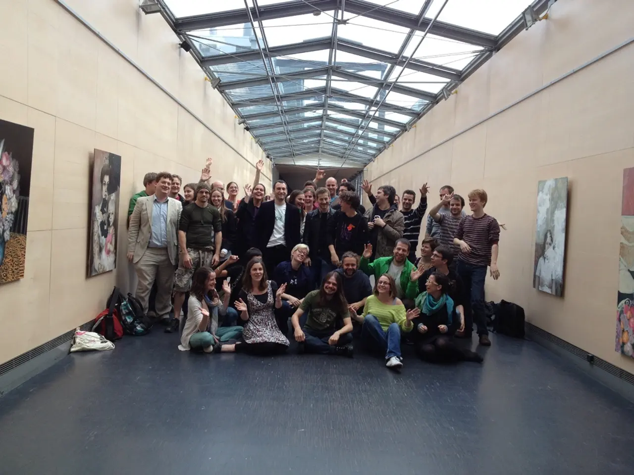 In the foreground of this image, there are group of people posing to the camera. Few are sitting...