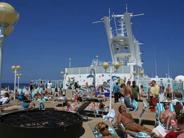 In the image a lot of people are taking rest on the chairs and in between the people there are some...