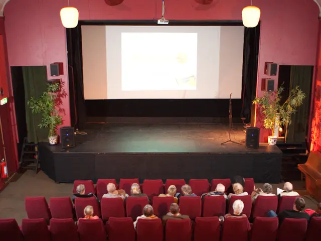 This picture is an inside view of an auditorium. In the center of the image we can see screen,...
