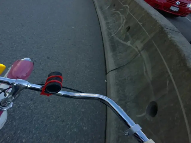 In this image I can see at the bottom it is the handle of a cycle. On the right side few vehicles...