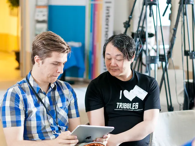 Here we can see two men and he is holding a apple device with his hands. There are stands and a...