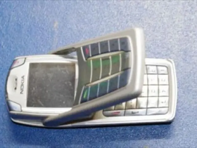 In this image there is a mobile phone on the floor, the background of the image is blue in color.