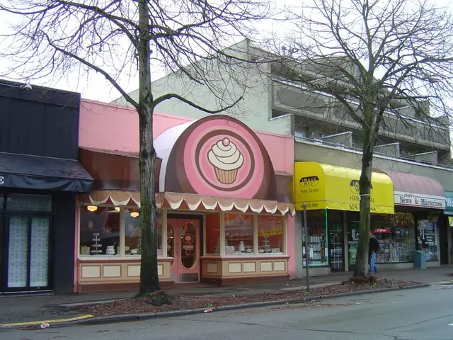 This picture shows a building and we see few stores and we see couple of trees and few name boards...