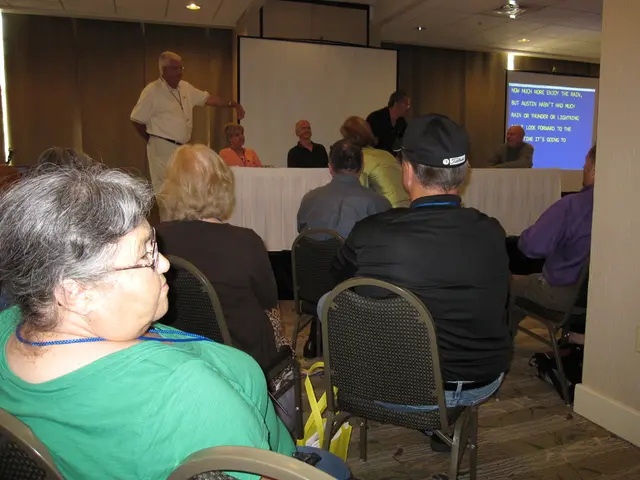 In this image there are group of persons sitting on a chair, in the front a man wearing a white...